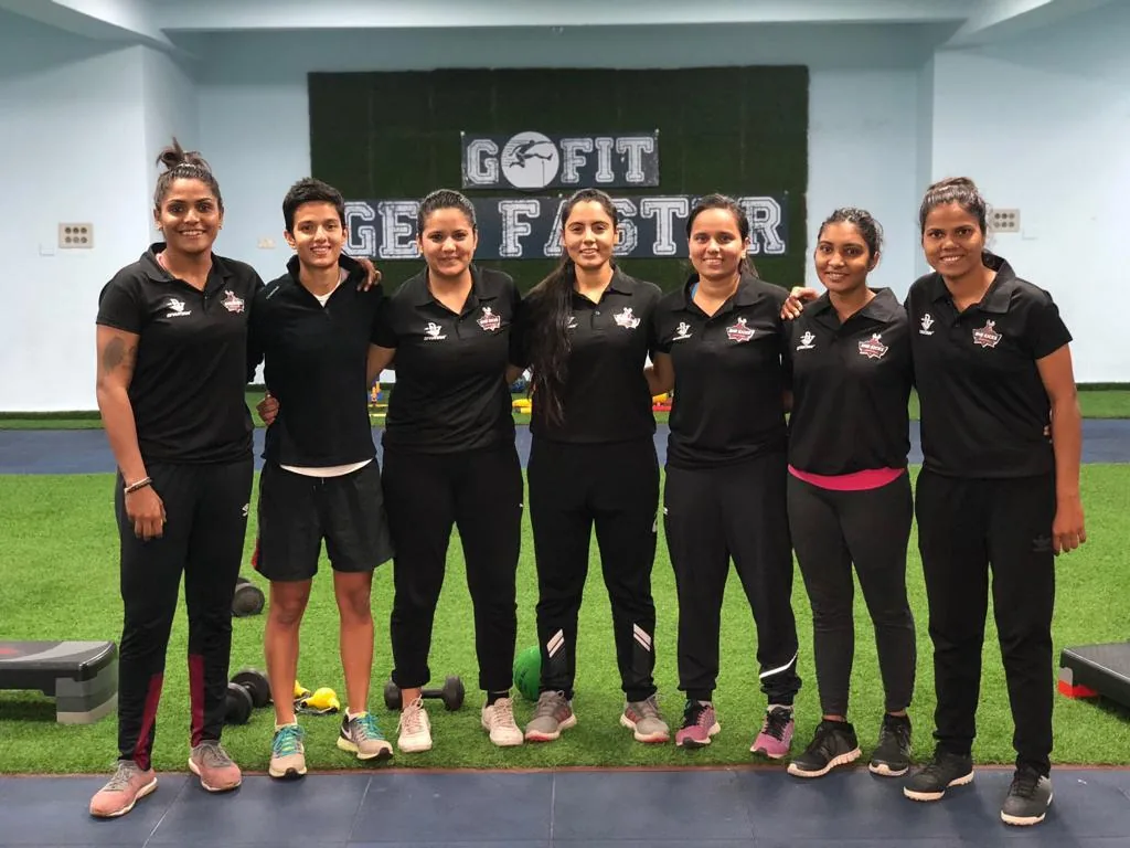 She Kicks coaches and players in black team polos posing together at a fitness gym