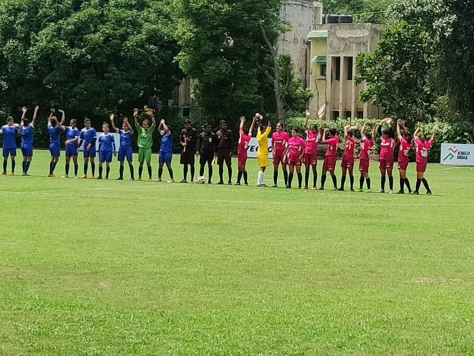 Two girls' teams lined up with match officials before a football match at a Khelo India ground