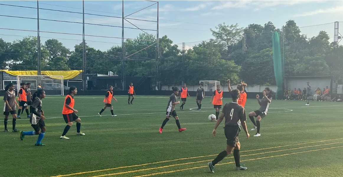Players in kit and bibs during an evening small-sided match on a floodlit turf pitch