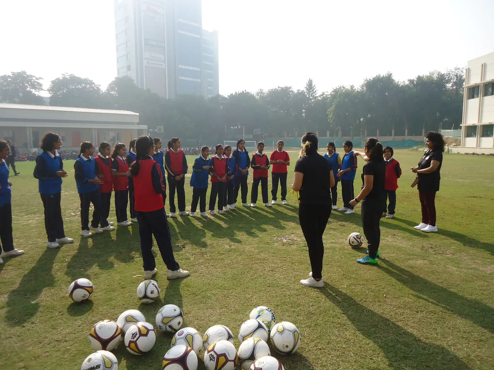 Two coaches briefing a circle of girls in bibs during a training session