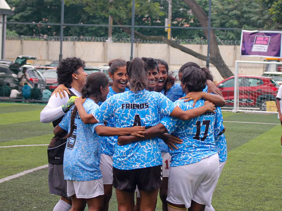 A team in blue kit huddling together on a turf pitch