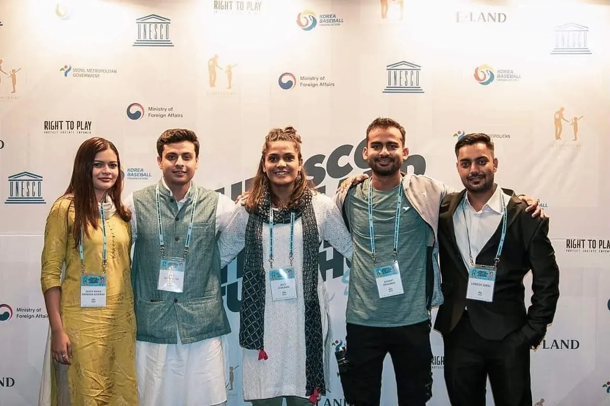 Aditi Chauhan with a group at a UNESCO event press wall.