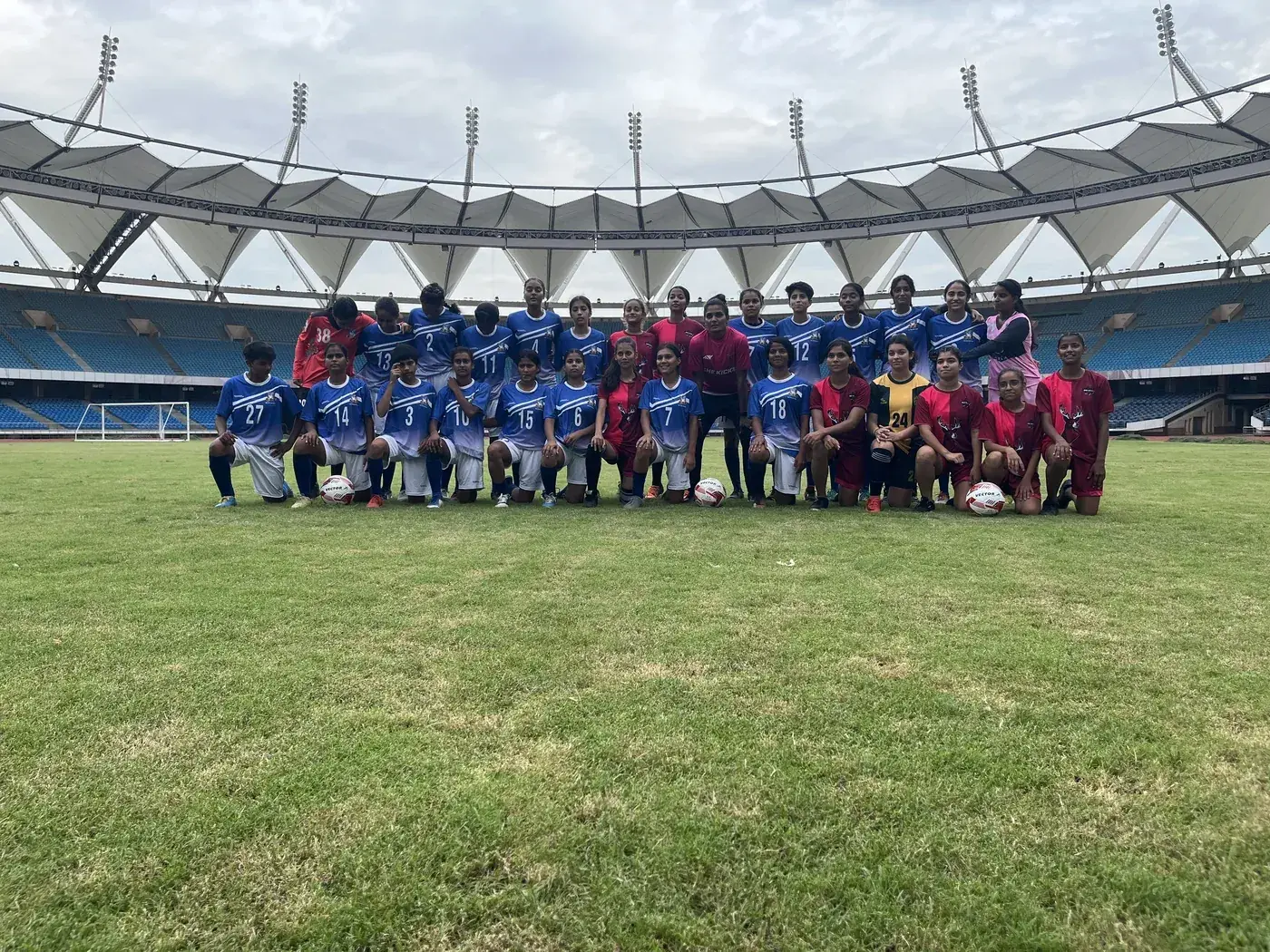 She Kicks Football League squads lined up for a team photo on a stadium pitch