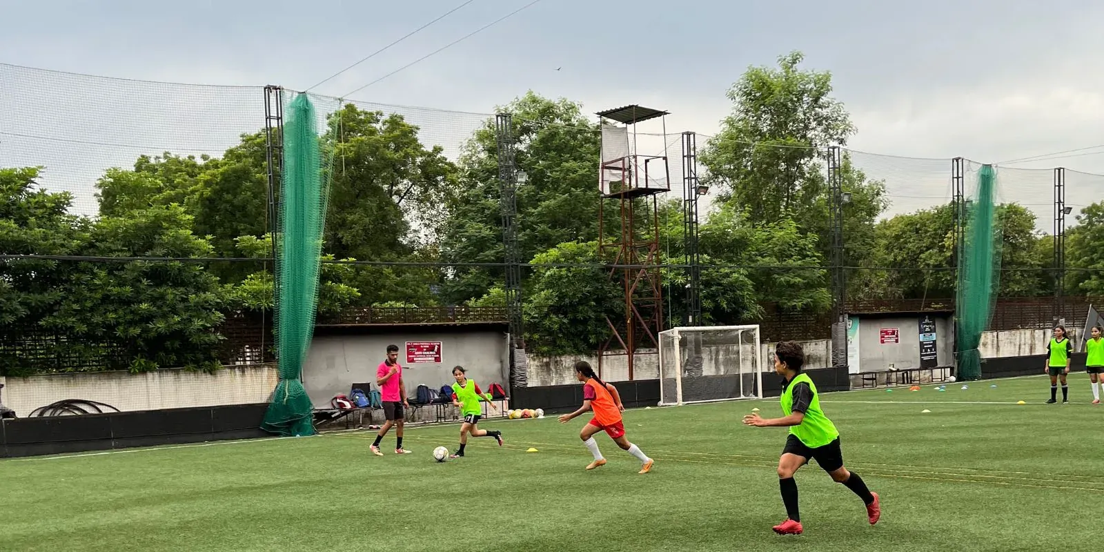 Women competing in a small-sided match on a turf pitch at a She Kicks Football League fixture