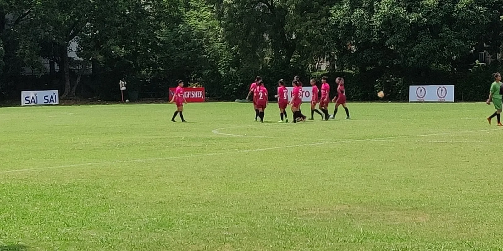 A girls' team in pink kit on the pitch at a football tournament