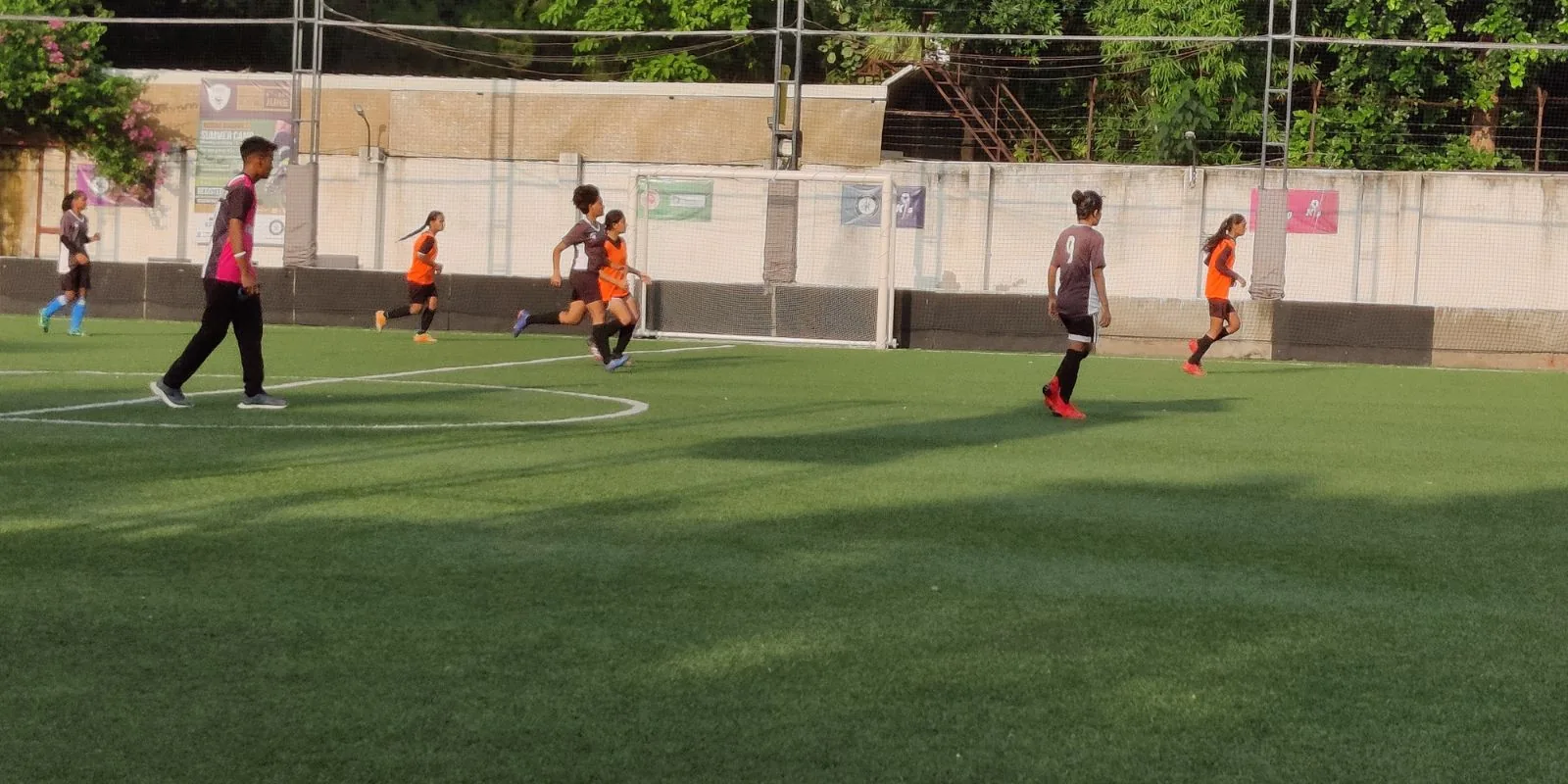 Players in maroon kit and orange bibs contesting the ball during a league match